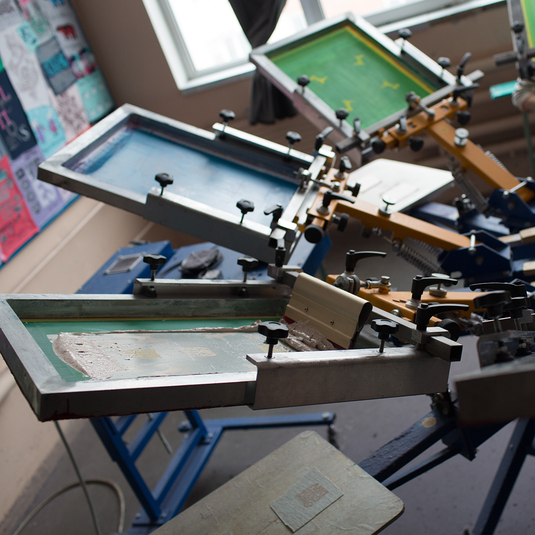 A person operating a printing machine, creating a print on a sheet of paper.