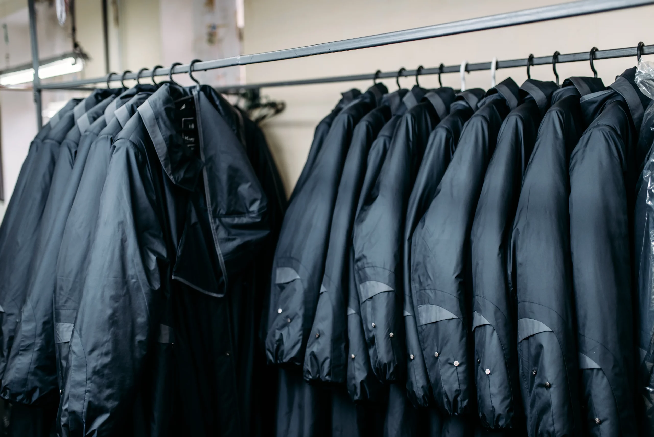A row of black raincoats neatly hung on a rack, ready to shield against the rain.